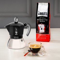 Káva připravená v konvici Bialetti New Moka Induction, servírovaná v průhledném šálku. Vedle balíček zrnkové kávy.