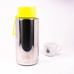 Keramický termohrnek s pítkem ze přední strany s lázeňskou kávou v pozadí.