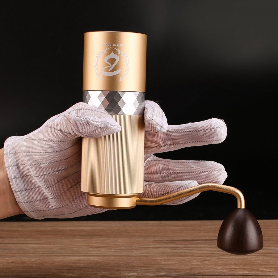 Obrácený ruční mlýnek Barista Space Premium Gold držen v ruce